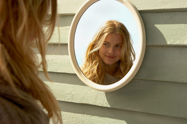 Young Woman Looking in Mirror outside
